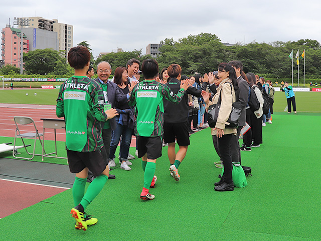 選手たちをハイタッチで迎える学園関係者