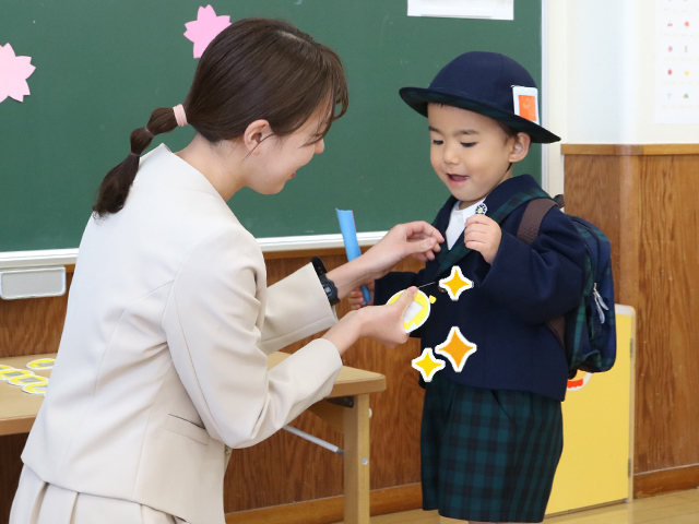 担任の先生にピカピカのバッジをつけてもらいます